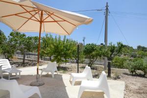 een groep witte stoelen en een paraplu bij Jardinu in Noto