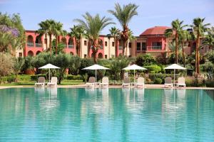 a pool with chairs and umbrellas in front of a resort at Iberostar Club Palmeraie Marrakech All Inclusive in Marrakesh