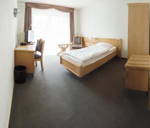 a bedroom with a bed and a desk and a window at Landgasthaus Fischer in Bad Nenndorf