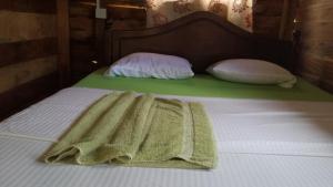 ein Bett mit einer grünen Decke mit zwei Kissen in der Unterkunft Sigiri Forest View in Sigiriya