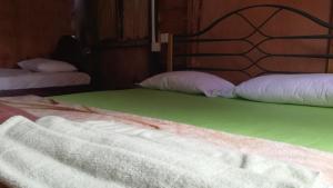 a bedroom with two beds with green sheets and white pillows at Sigiri Forest View in Sigiriya