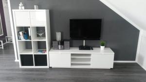 ein Wohnzimmer mit einem weißen Entertainment-Center mit einem TV in der Unterkunft Ferienwohnung Wesertraum in Hannoversch Münden