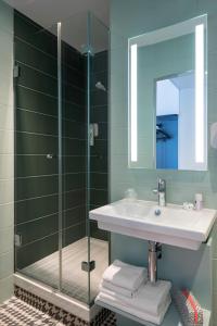 a bathroom with a shower, sink, and mirror at Ibis Styles Paris Gare Saint Lazare in Paris