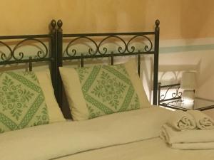 a bed with green and white pillows on it at Su Recreu in Bosa Marina