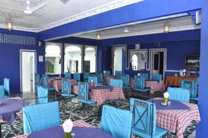 a dining room with blue tables and blue chairs at Hotel Gangaur Palace in Udaipur