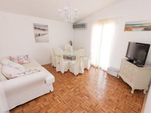a white living room with a table and a tv at Apartments Marija in Vir