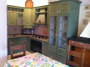 a kitchen with green cabinets and a table in it at Appartamenti Marilu in La Caletta
