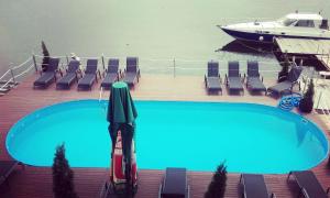 a large swimming pool with chairs and a boat at Pensiunea Oliver in Orşova
