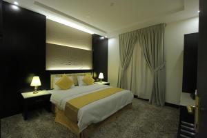 een hotelkamer met een groot bed met gele kussens bij Qasr Rayana Aparthotel in Buraydah