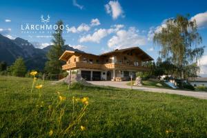 a house in the mountains with a green lawn at Appartements Lärchmoos in Ramsau am Dachstein