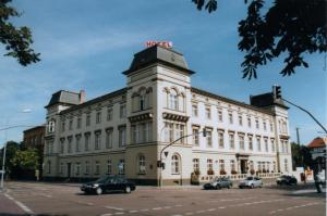 a large white building with cars parked in front of it at Hotel "Stadt Köthen" in Köthen