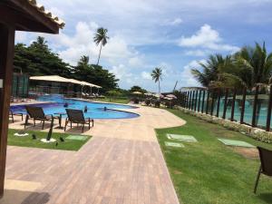 a swimming pool with tables and chairs and the ocean at Tabatinga Residence Apart Hotel in Jacumã
