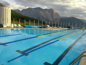 a large blue swimming pool with mountains in the background at Hotel Sud Ovest in Sestriere