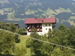 una casa con techo rojo en la cima de una colina en Tatscherhof, en Hainzenberg