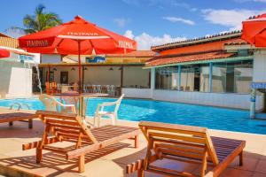 una piscina con 2 sillas y una sombrilla en Garça Branca Praia Hotel, en Porto Seguro