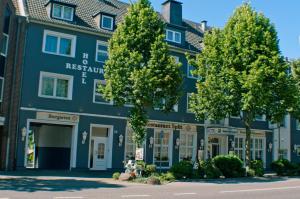 ein blaues Gebäude mit Bäumen davor in der Unterkunft Hotel Stadt Emmerich in Emmerich