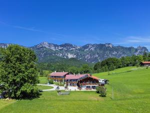 a large house in a field with mountains in the background at Pension Loiplstüberl in Bischofswiesen