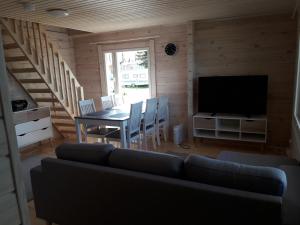 a living room with a couch and a table with a television at Ristijärven Pirtti Cottage Village in Ristijärvi