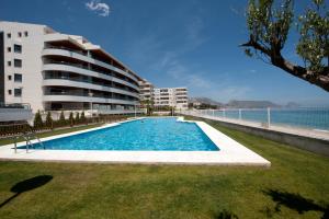 a swimming pool in front of a building next to the ocean at Apartamentos Calpestabili in Altea