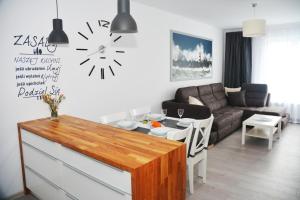 a living room with a couch and a clock on the wall at Apartament Solna 11 in Kołobrzeg
