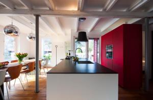 a kitchen with red cabinets and a black counter top at Logbua - House on the Sea in Åna-Sira