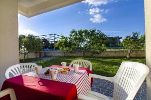 a table with a red and white table cloth on a patio at Apartments Glavan in Privlaka