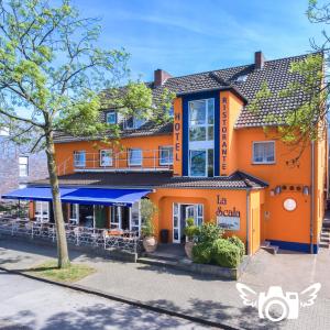 ein orangefarbenes Gebäude mit einem Restaurant in der Straße in der Unterkunft Hotel La Scala in Gelsenkirchen