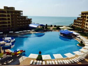 a large swimming pool with chairs and umbrellas at Apartments Aheloy Palace in Aheloy