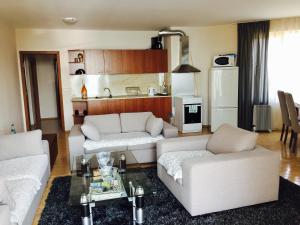 a living room with two white couches and a kitchen at Apartments Aheloy Palace in Aheloy