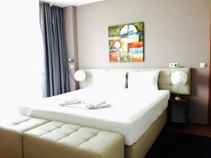 a bedroom with a white bed and a couch at Apartments Aheloy Palace in Aheloy