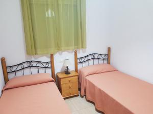 2 Betten in einem Zimmer mit grüner und orangefarbener Bettwäsche in der Unterkunft Apartamento Costa Marina III Magic World in Oropesa del Mar