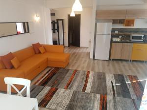 sala de estar con sofá naranja y cocina en Fundeni Apartments en Bucarest