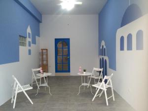 una habitación con sillas y mesas blancas y una pared azul en Love 3 cubed, en Magong