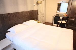 a bedroom with a large white bed and a desk at D'Rami in Almaty