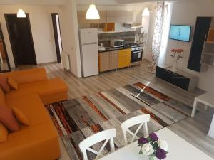 ブカレストにあるFundeni Apartmentsのリビングルーム(オレンジ色のソファ付)、キッチンが備わります。