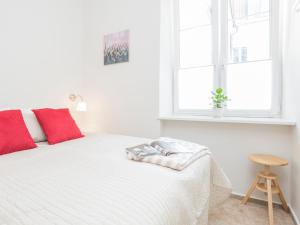 ワルシャワにあるDelightful New Town Square Apartmentのベッドルーム1室(白いベッド1台、赤い枕、窓付)