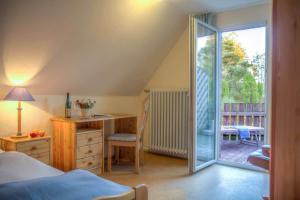 a bedroom with a bed and a desk and a sliding glass door at Biohotel Spöktal in Bispingen
