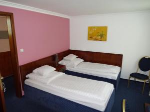 a hotel room with two beds and a chair at Atlanta Budget Darmstadt in Darmstadt