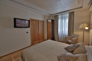 een slaapkamer met een bed, een stoel en een televisie bij Aber Apartment in Belgrado