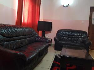 a living room with a leather couch and a tv at Maison Rose in Douala