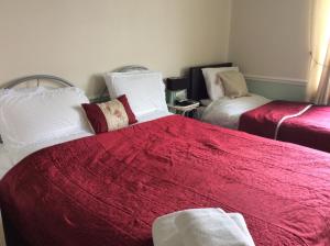 a bedroom with two beds with red and white blankets at Alma Lodge Guest House in Plymouth