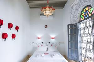 a bedroom with a bed with a chandelier and a window at Riad Yamcha in Meknès