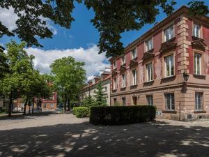 a large brick building with trees in front of it at Delightful New Town Square Apartment in Warsaw