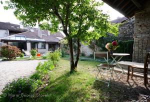 a table and chairs in a yard with a tree at La Victoire de Noyers in Noyers-sur-Serein