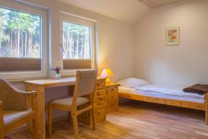 een slaapkamer met een bureau, een bed en 2 ramen bij Biohotel Spöktal in Bispingen