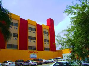 un edificio amarillo y rojo con coches estacionados en un estacionamiento en Hotel Le-Gar en Monterrey
