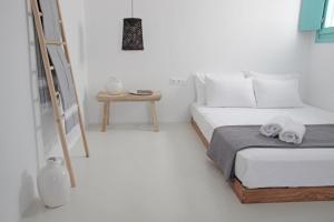 a white bedroom with a bed and a ladder at Ploes Seaside Houses in Plaka