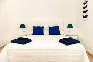 a white bedroom with blue pillows on a white bed at Apartamento Filla in Puerto del Carmen