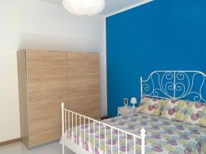 a bedroom with a blue accent wall and a bed at Appartamento Aria 150m dal mare in Castelsardo