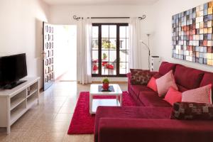a living room with a red couch and a tv at Apartamento Filla in Puerto del Carmen +12 photos